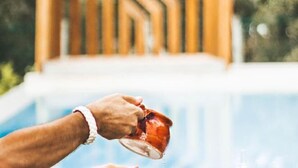 A hand pouring liquid from a glass into a cup near a pool. - Luz Charming Houses (Fatima)