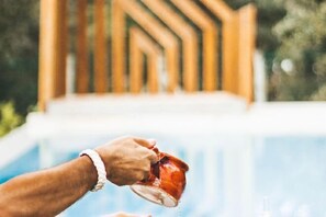 A hand pouring liquid from a glass into a cup near a pool. - Luz Charming Houses (Fatima)