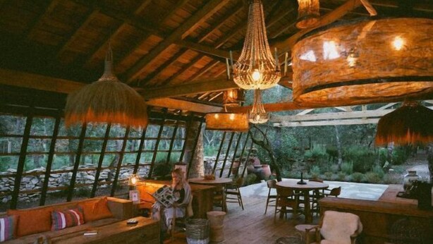 A rustic wooden interior with a large window, a wooden sofa, and a dining table. - Luz Charming Houses (Fatima)