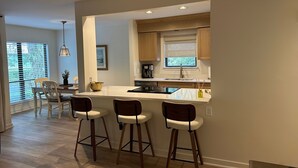 Une cuisine moderne avec un coin bar, des meubles en bois et une grande fenêtre.
