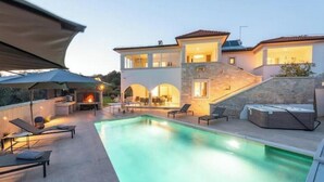 Una casa moderna con piscina, mobiliario de exterior y chimenea.