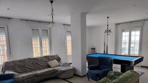 Ein Wohnzimmer mit Billardtisch, einer Couch und einem grünen Sofa.