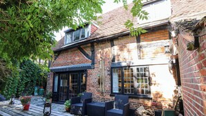 A brick building with a tiled roof, a wooden table with chairs, and potted plants. - The Old House (Southampton)