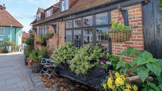 A traditional brick building with multiple windows and hanging flower baskets. - The Old House (Southampton)