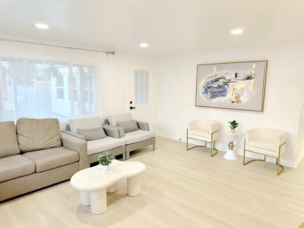 A modern living room with a beige sofa, a white bench, and two white armchairs. There is a painting on the wall and a small table with a plant. - 2 Houses - 5 Bed Rooms 4 Bath - 2 Kitchens - Single Level - 2 Private Acres (Hillsboro)