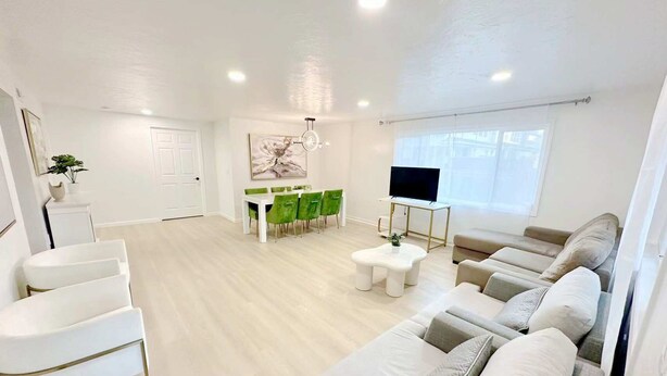 A modern living room with a sofa set, a dining table with chairs, a TV on a stand, and a large window. - 2 Private Acres - 2 Houses - 5 Bed Rooms 4 Bath - 2 Kitchens - Single Level  (Hillsboro)