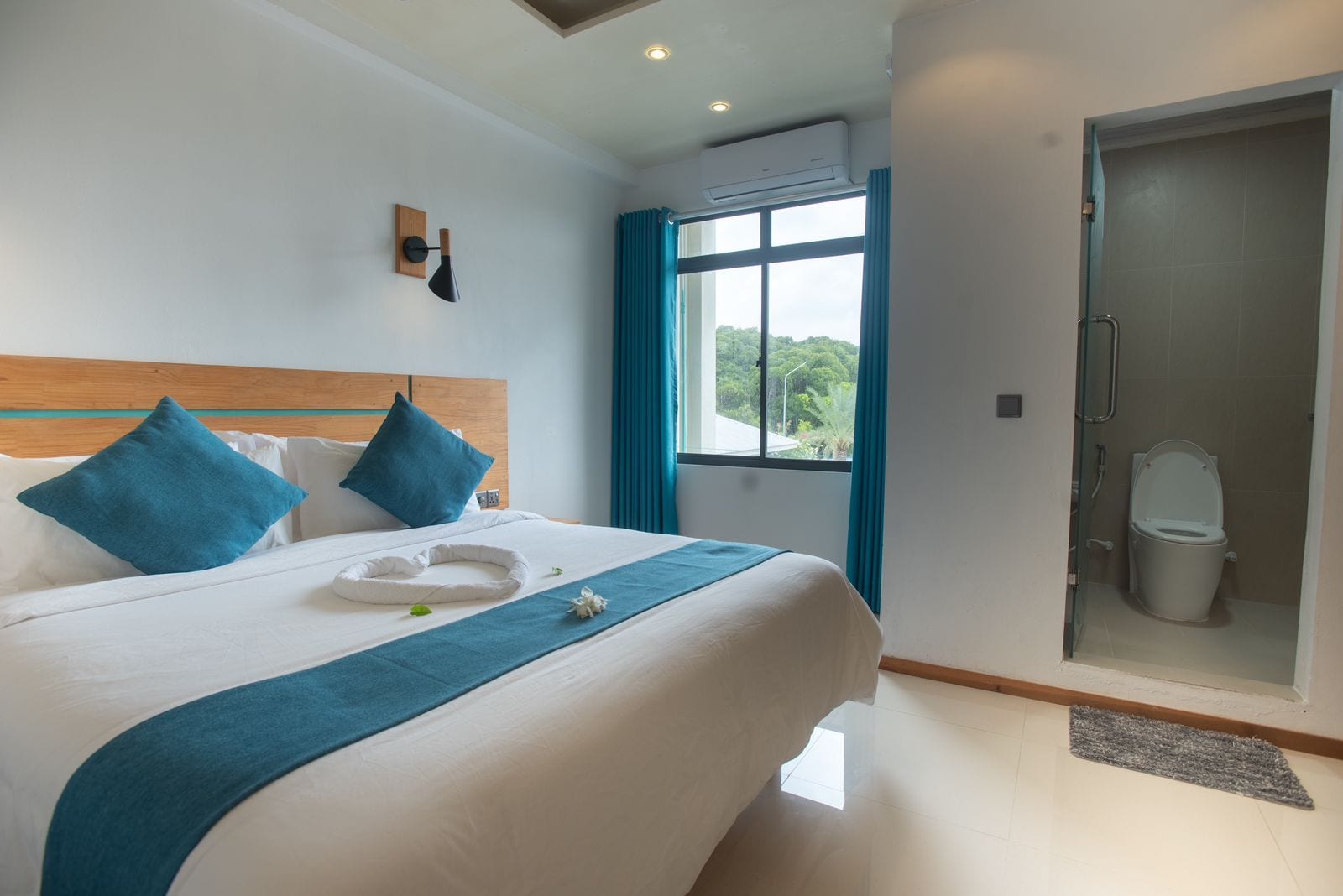 A hotel room with a bed, a shower, and a window with curtains.
