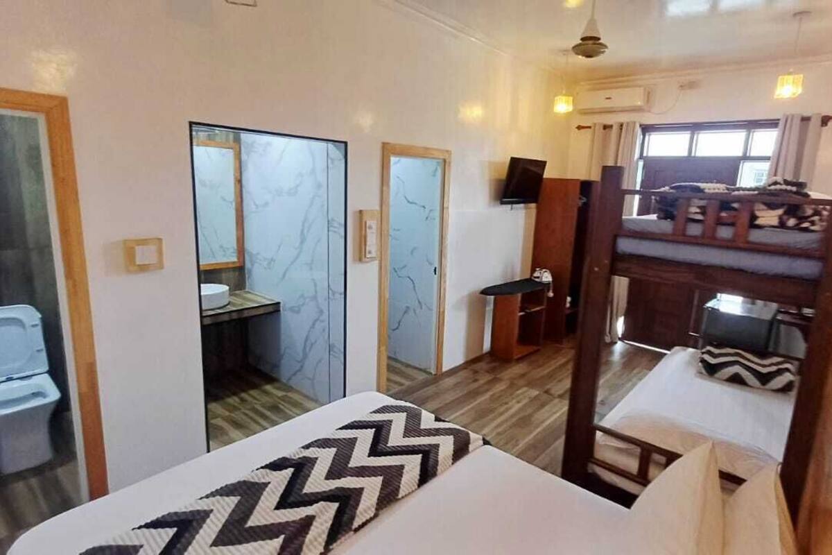 A room with a bunk bed, a small desk, a mirror, and a window.
