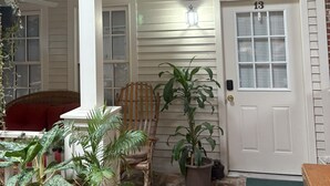 A covered porch with a wooden chair, potted plants, and a white door marked with the number 13. - 2-bedroom apartment in wonderful Lorain with AC (Lorain)