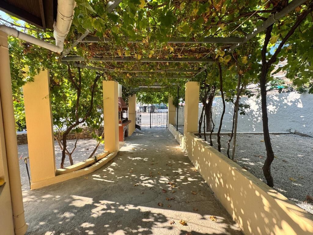 A covered walkway with a concrete floor, yellow walls, and a metal railing.