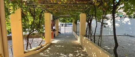 A covered walkway with a concrete floor, yellow walls, and a metal railing.