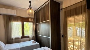 Ett hotellrum med två sängar, en garderob och ett stort fönster med gardiner.