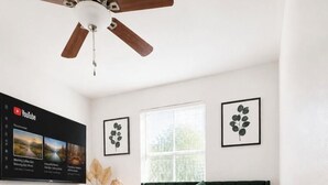 A bedroom with a bed, a ceiling fan, a TV displaying YouTube, and framed artwork on the wall. - Entire Spacious and beautiful 5 Bedroom House (Garland)