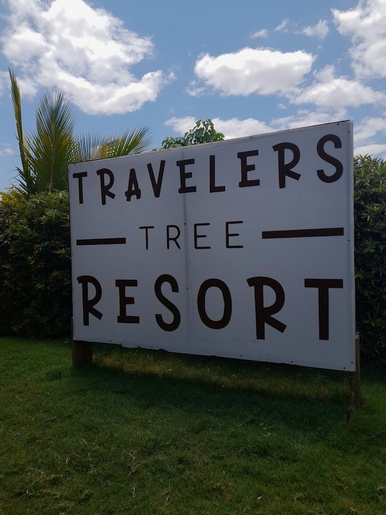 Un panneau indiquant l’emplacement du complexe hôtelier Travelers Tree Resort.