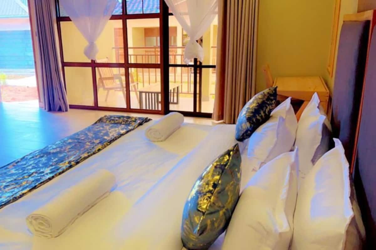 A hotel room with a large bed, a view of the outdoor area, and a balcony.