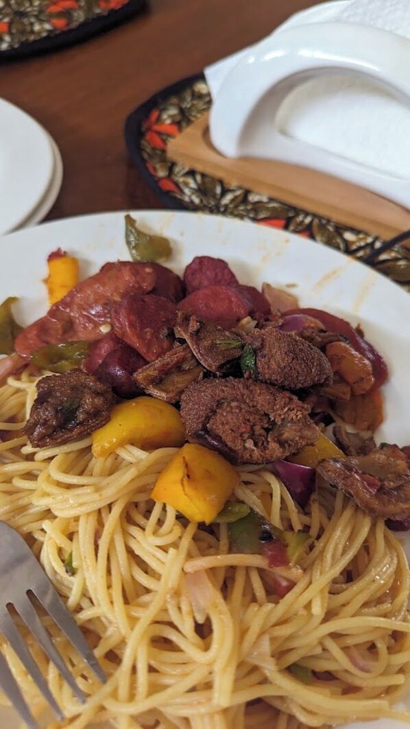 A plate of spaghetti with meat and vegetables.