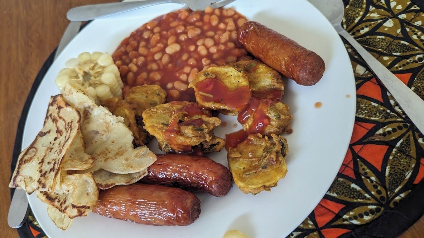 A plate with beans, sausages, fried plantains, and fried plantain chips.