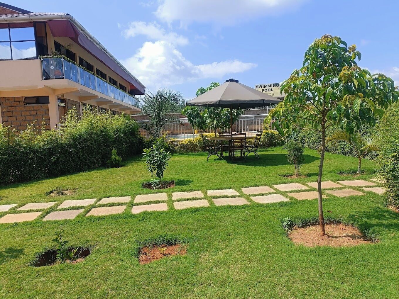 A courtyard with a swimming pool, a covered seating area, and a building with a balcony.
