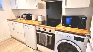 A compact kitchen with a dishwasher, washing machine, microwave, and a toaster.