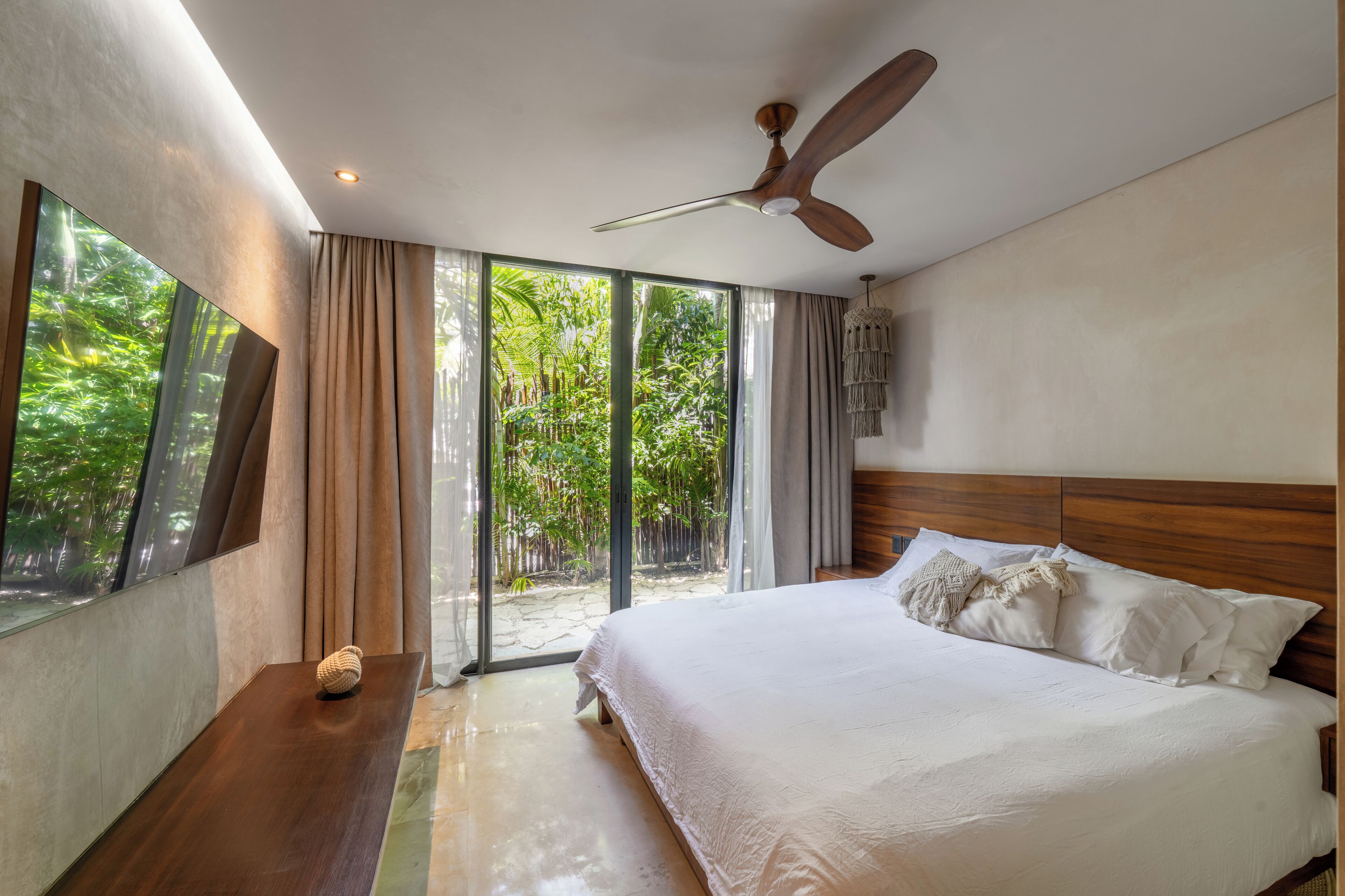 Ein Schlafzimmer mit einem großen Bett, einem Holzkopfende und einem Deckenventilator.