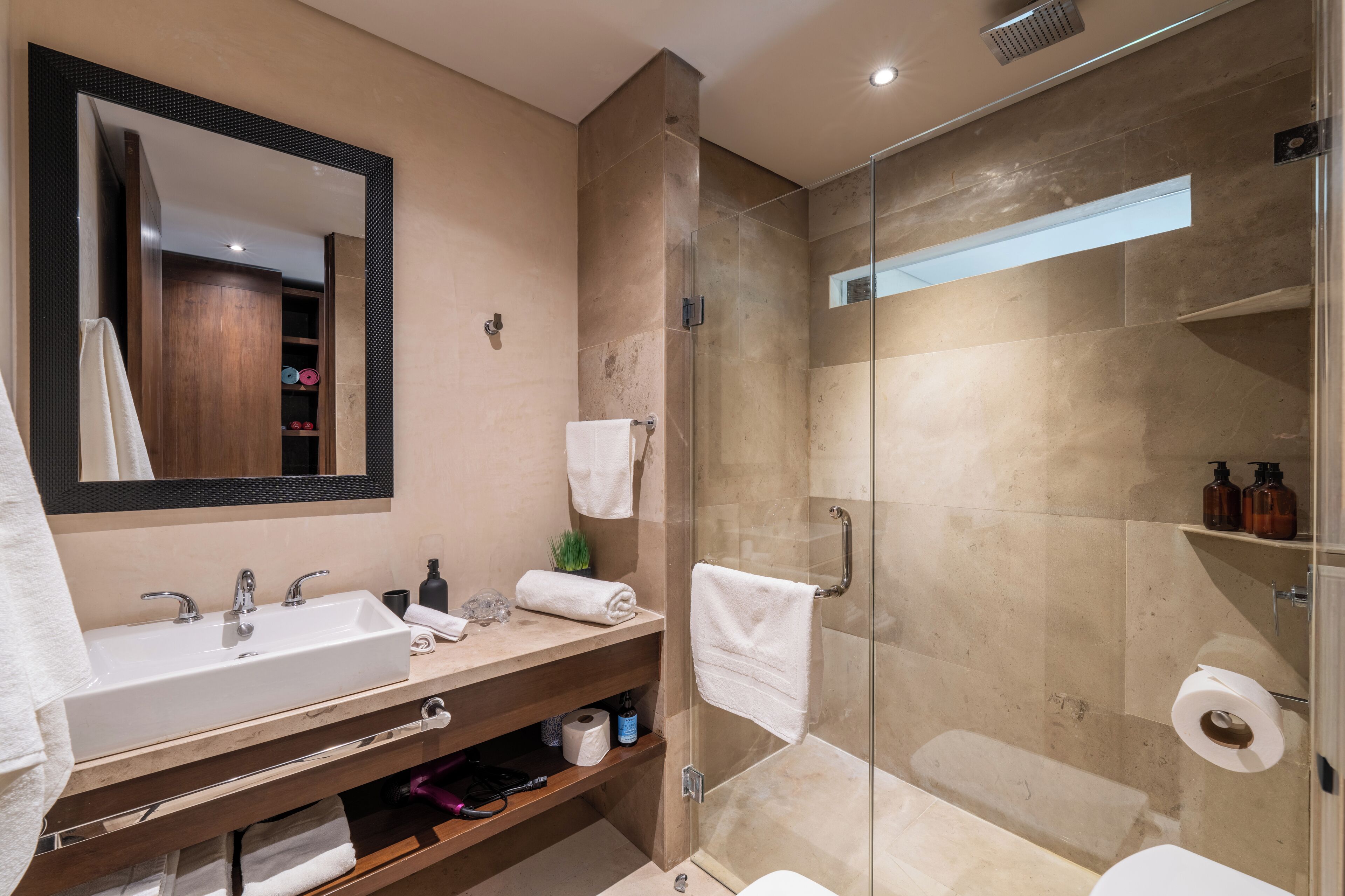 Une salle de bain moderne avec un grand lavabo, un miroir et une douche à parois de verre.