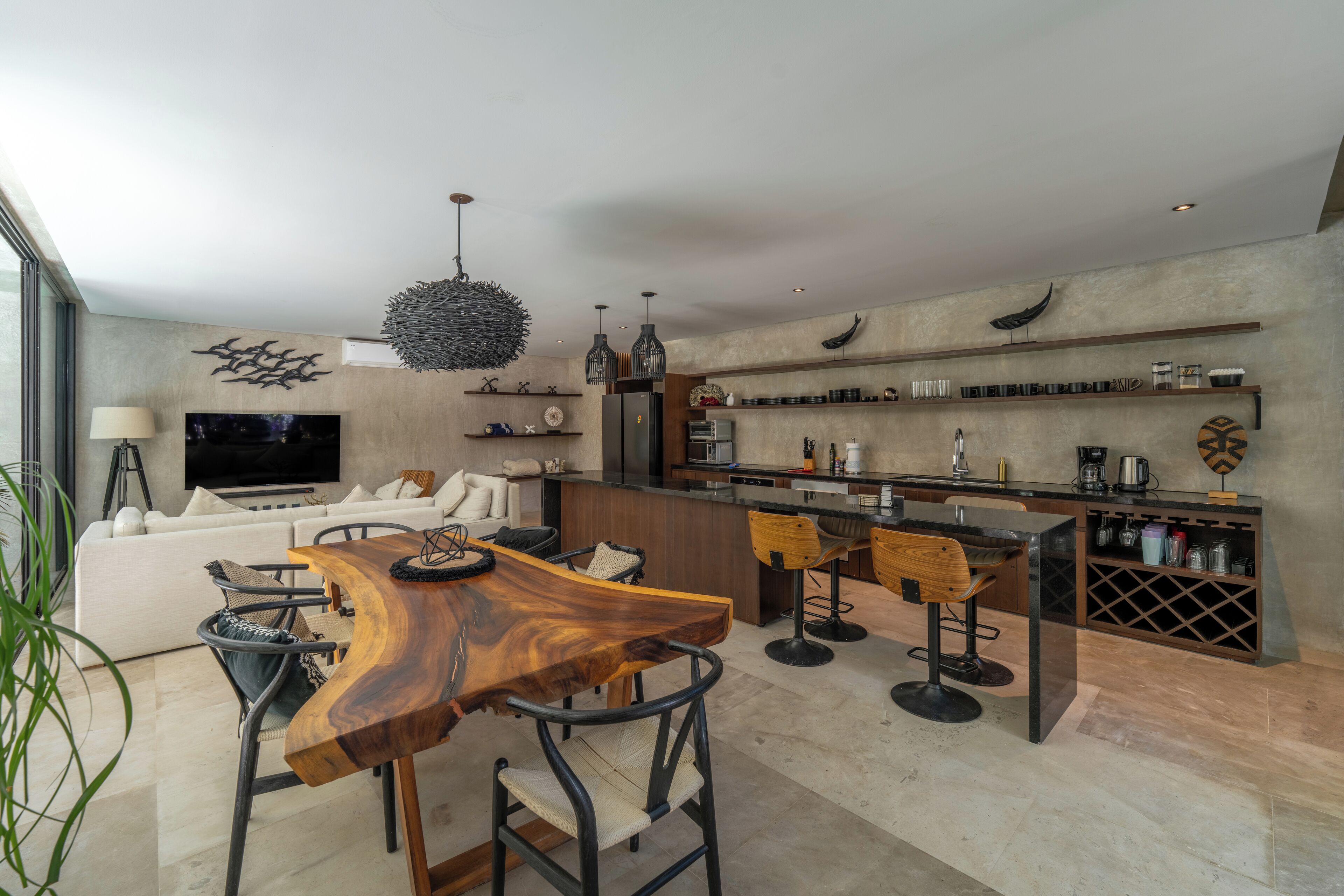 A modern kitchen with a dining area, a sofa, and a TV.
