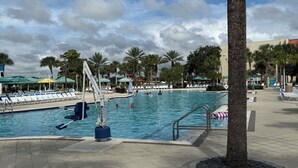 Zona de piscina con sillas de descanso, puesto de salvavidas y palmeras.
