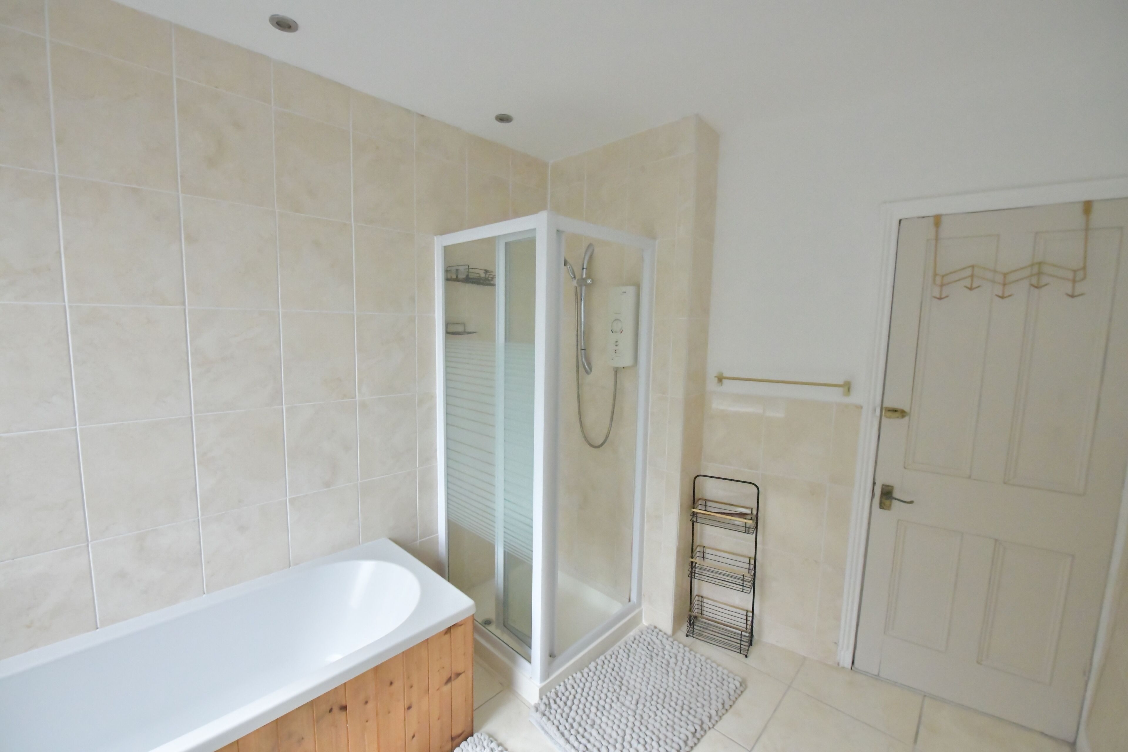 Une salle de bain avec une baignoire, une douche à parois de verre et une porte blanche.