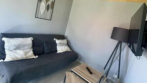 Una sala moderna con un sofá gris oscuro, una pequeña mesa de centro de madera y una lámpara de pie.