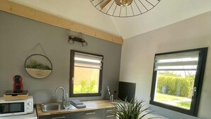 Una cocina moderna con una mesa de madera, un microondas, un lavamanos y una ventana con vistas a zonas verdes.