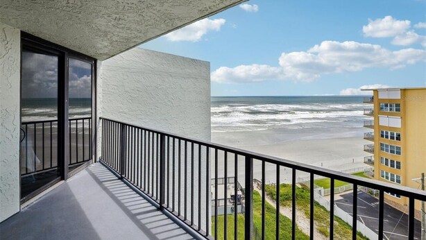 A balcony with a view of the ocean and a building across the street.