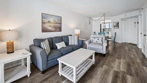A living room with a gray sofa, a white coffee table, and a painting on the wall.