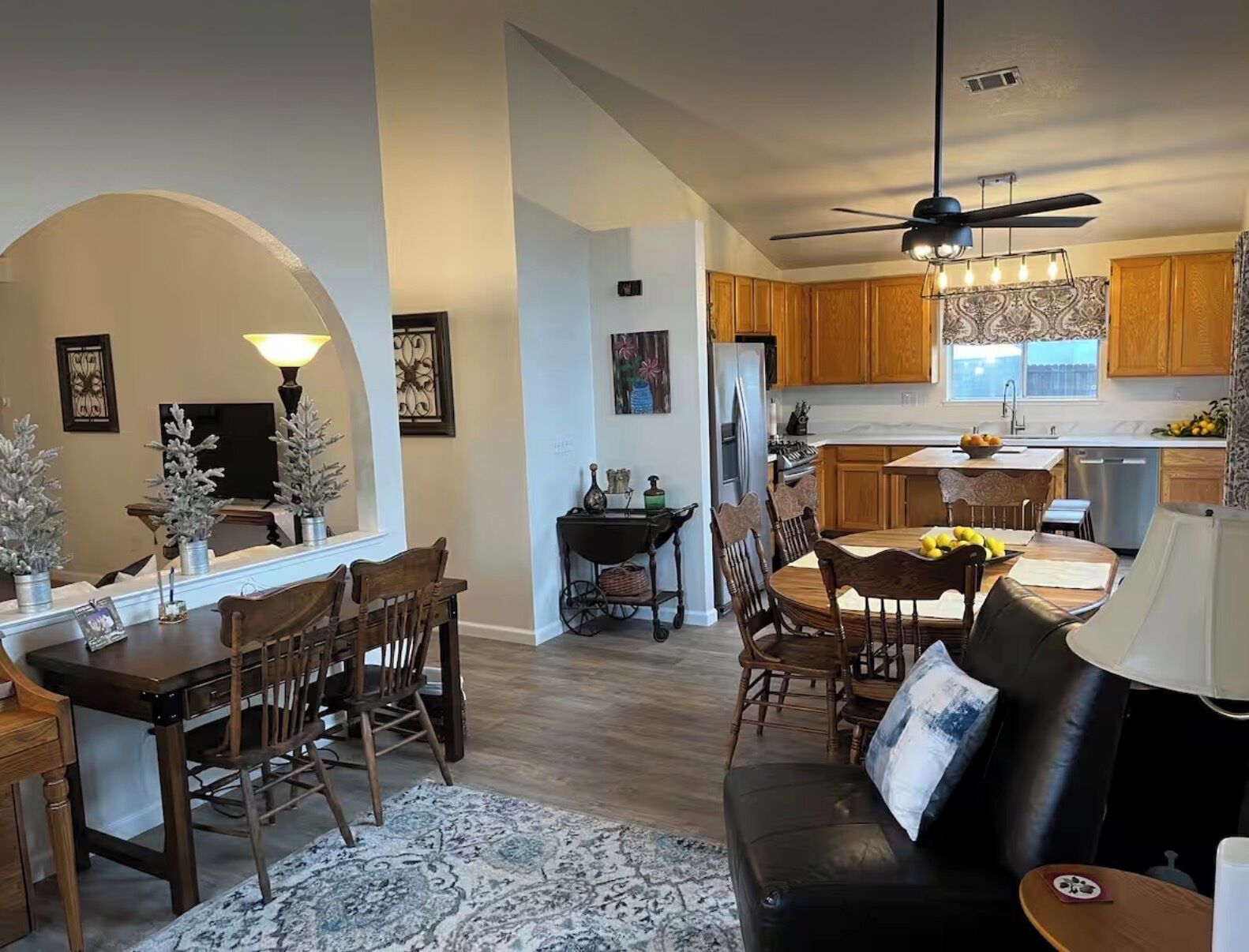 A spacious living room with a fireplace, a dining area with wooden furniture, and a kitchen with wooden cabinets and a modern design.
