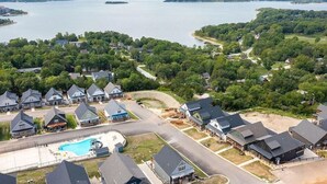 A residential area with houses, a swimming pool, and a lake in the background.