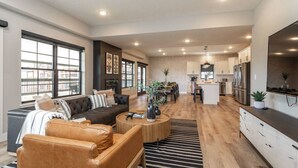 A spacious living area with a sofa, coffee table, and a kitchen in the background.