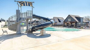 A water slide structure, a pool, and residential buildings.