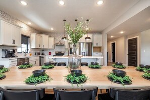 Une cuisine moderne avec des meubles blancs, un îlot central agrémenté d’un vase, et des bols noirs contenant des plantes vertes.