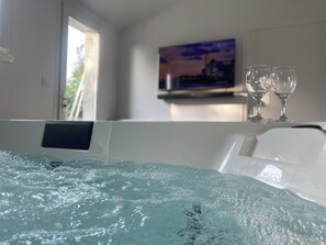 A hot tub with two glasses on the edge, a painting on the wall, and a window with daylight. - Private SPA & Garden - 10 min from Mont St-Michel (Pontorson)