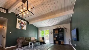Un salon spacieux avec un plafond haut, une grande fenêtre et un coin salon confortable.