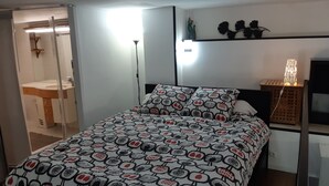 Un dormitorio con una cama, una mesita de noche, un estante en la pared y un espejo.