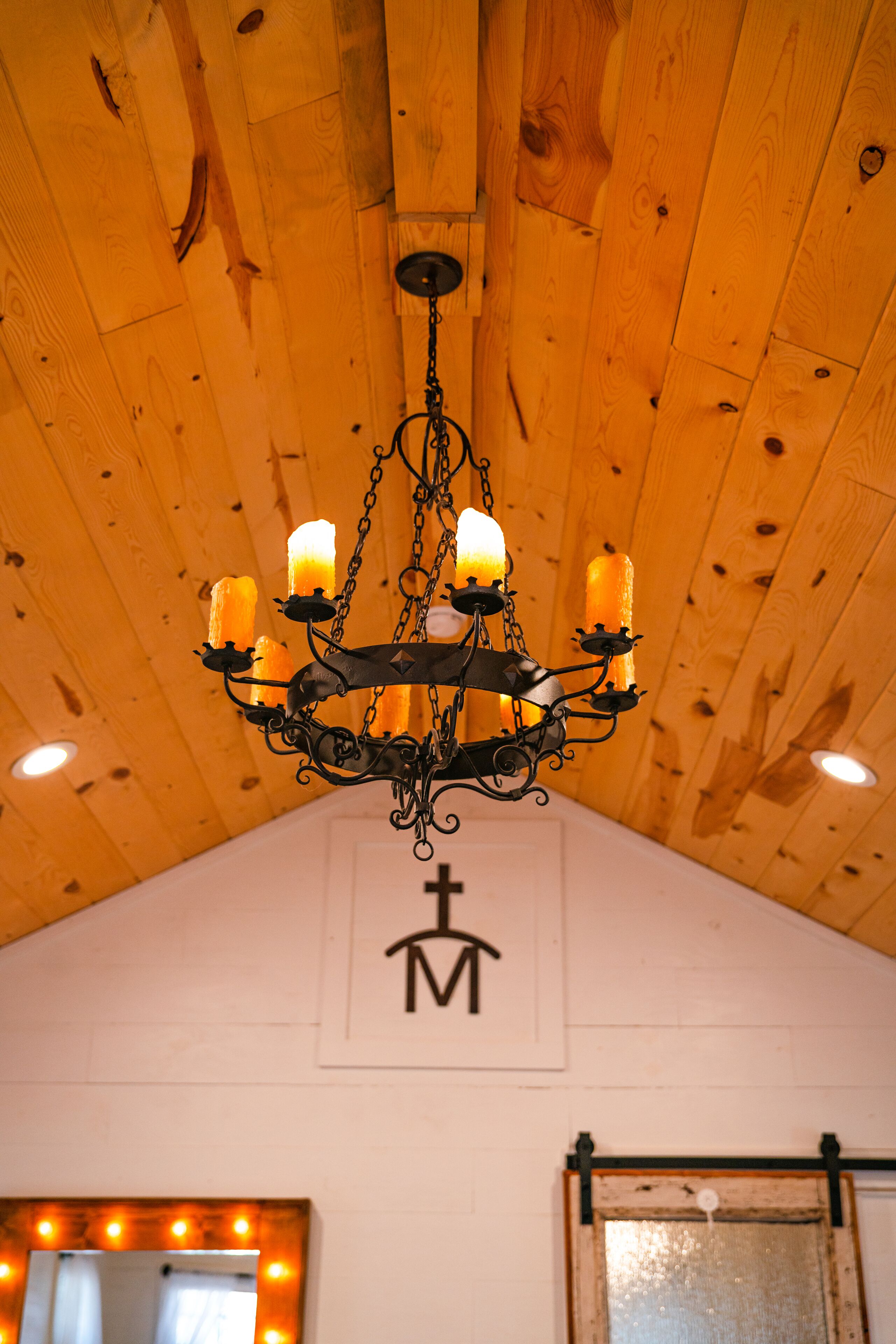 A chandelier with four candles hanging from a wooden ceiling.