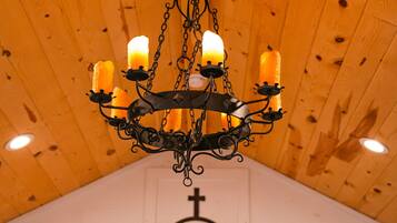 A chandelier with four candles hanging from a wooden ceiling.