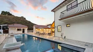Una piscina con lettini e un edificio con un balcone.