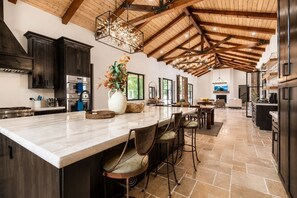 A spacious kitchen with a large island, dark cabinetry, and a vaulted ceiling. - Hacienda Style Home, Swimming Pool, Hot Tub, Outdoor BBQ Area, Fire Pits (Salinas)