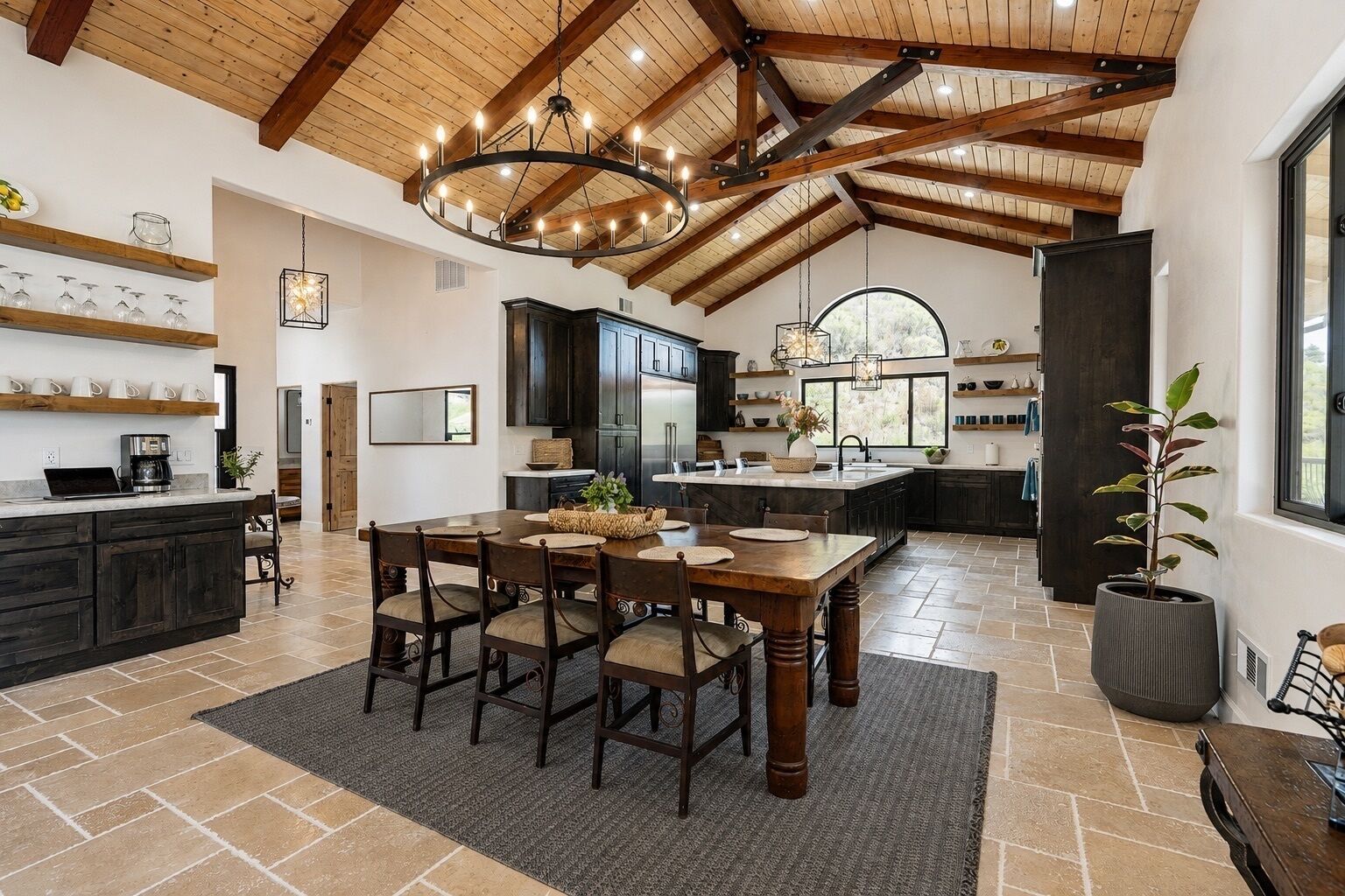A spacious kitchen with a large island, dark wooden cabinets, and a vaulted ceiling with exposed beams.