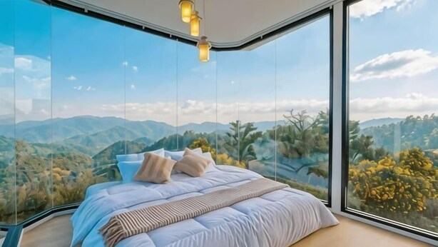 A bedroom with a large bed, a view of the mountains, and a hanging light fixture.