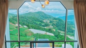 A room with large windows offering a view of green hills and solar panels.