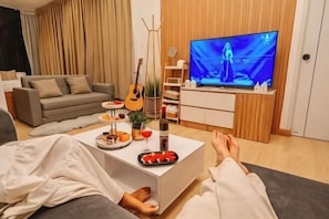 A living room with a sofa, a coffee table with snacks, a guitar, and a TV.