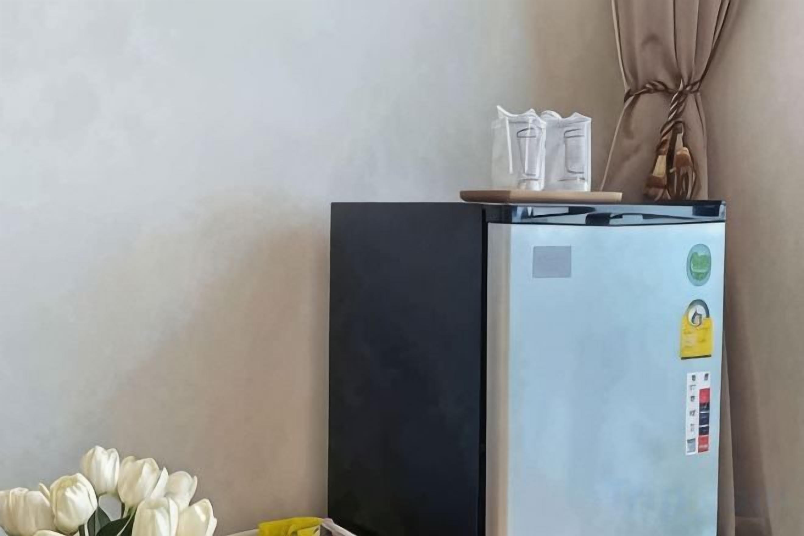 A refrigerator with a black door and a light blue door, placed against a wall with a curtain.