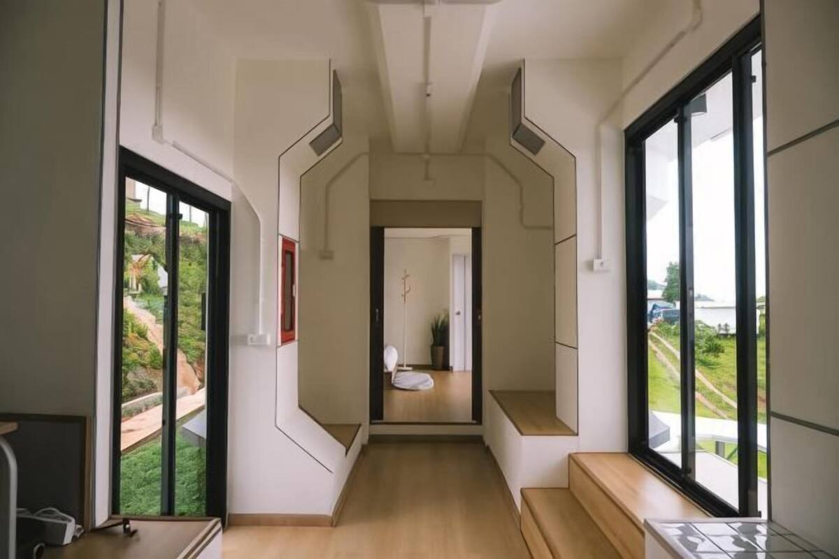 A hallway with a view of a garden, a bench, and a door leading to a bathroom.